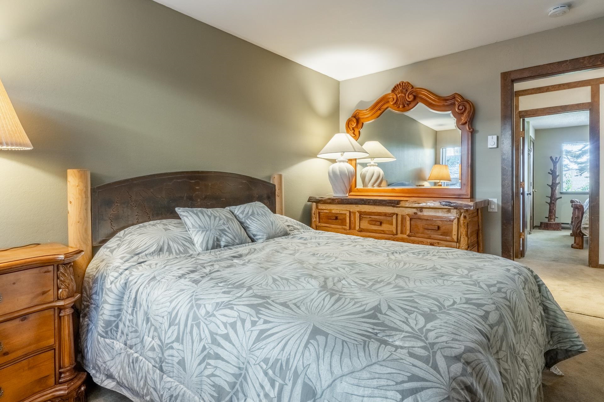 94 John Muir Road, Unit 132 Mammoth Lakes, CA 93546 - Photo 31 of 58 Bedroom featuring wood-finish flooring, a decorative wood-framed mirror, and a wood-frame doorway leading to an additional space