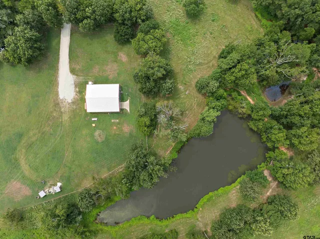 an aerial view of residential house with outdoor space and trees all around