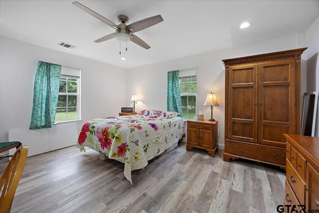 a bedroom with a bed and a dresser with wooden floor