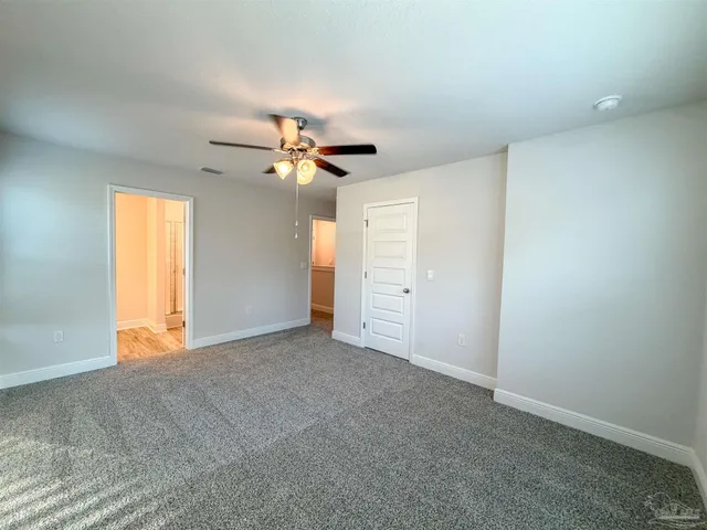 an empty room with closet and a ceiling fan
