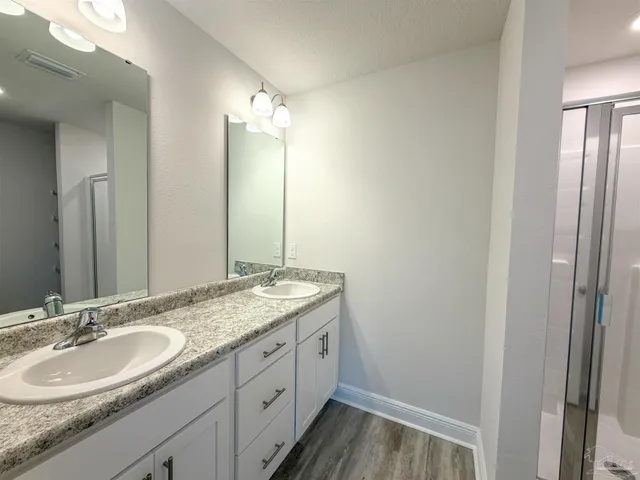 a bathroom with a granite countertop double vanity sink and mirror