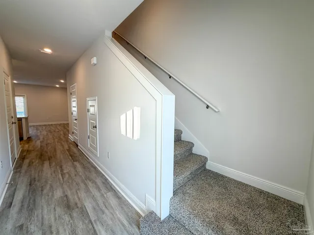 a view of a hallway with wooden floor and staircase