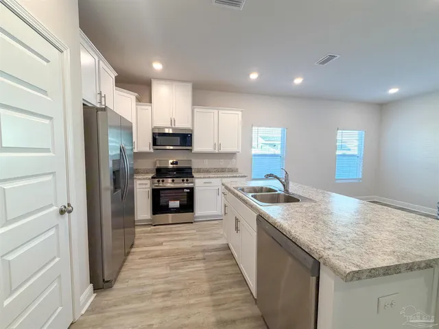 a kitchen with stainless steel appliances granite countertop a stove a refrigerator and a sink