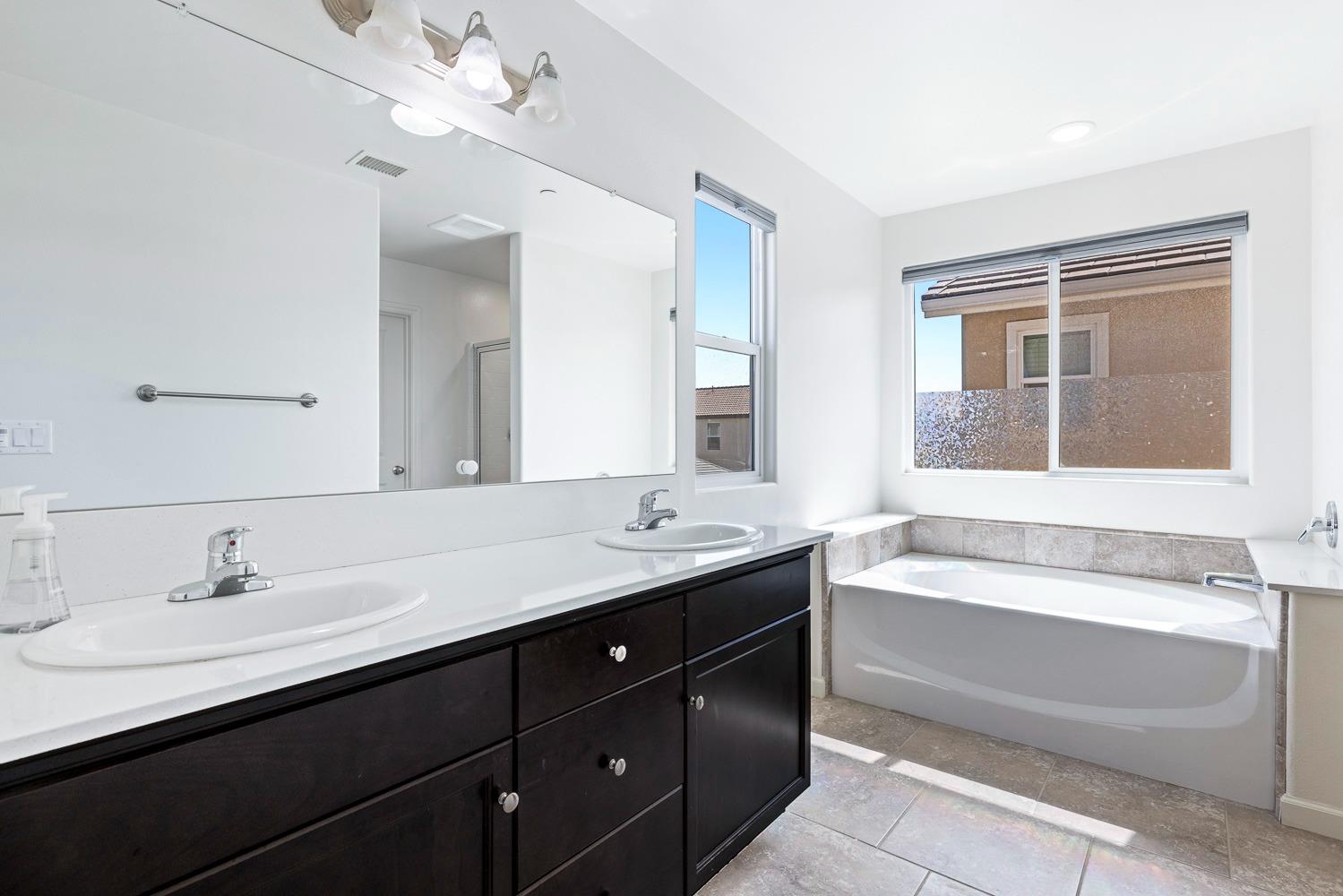 3606 Parkstone Way Clovis, CA 93619 - Photo 24 of 38 a bathroom with a tub double vanity sink and mirror