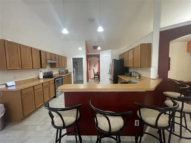 a kitchen with a dining table chairs refrigerator and microwave