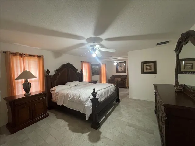 a spacious bedroom with a bed and dresser with mirror