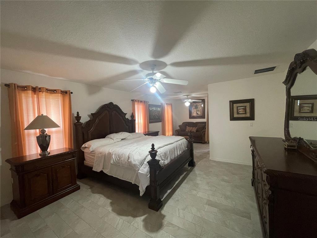 8759 Southwest 52nd Court Ocala, FL 34476 - Photo 9 of 20 a spacious bedroom with a bed and dresser with mirror