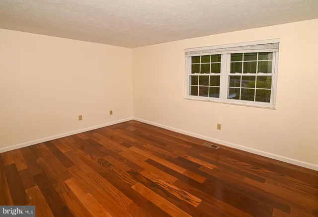 a view of empty room with wooden floor and windows
