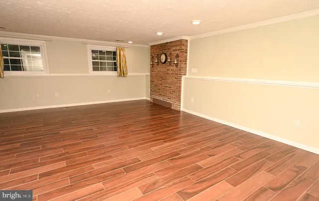 a view of an empty room with wooden floor and a sink