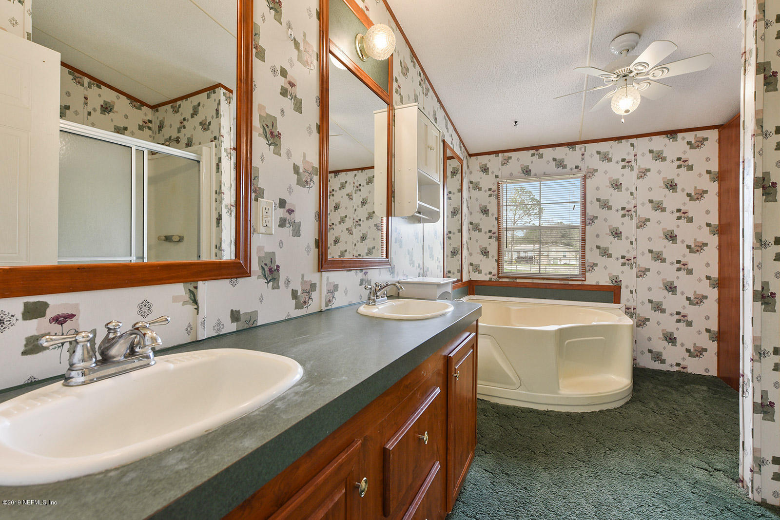 75302 Edwards Road Yulee, FL 32097 - Photo 13 of 25 a bathroom with a granite countertop sink a large mirror and a bathtub