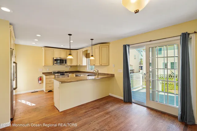 a kitchen with stainless steel appliances granite countertop a stove a refrigerator and a view of living room