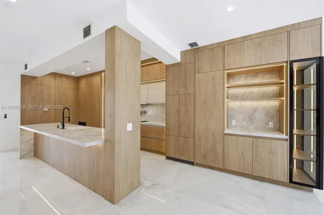 a large kitchen with granite countertop a large counter top and stainless steel appliances