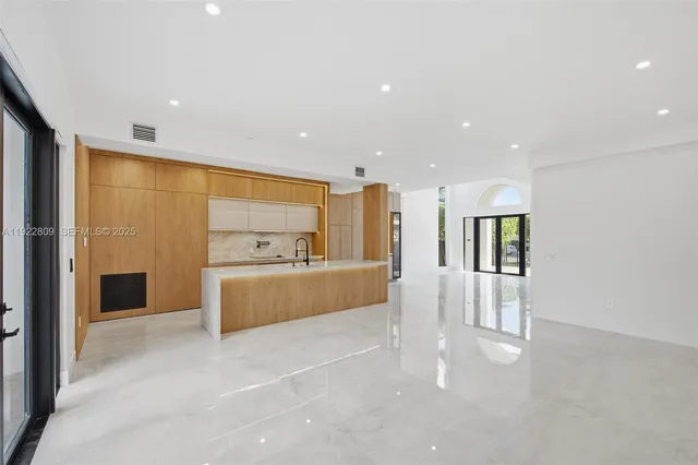 a large white kitchen with granite countertop a large window
