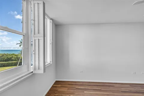 a view of an empty room with a window and wooden floor