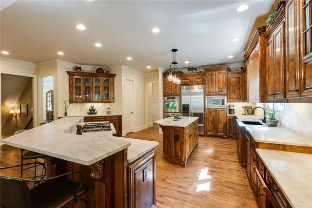 a kitchen with stainless steel appliances granite countertop sink stove refrigerator dining table and chairs