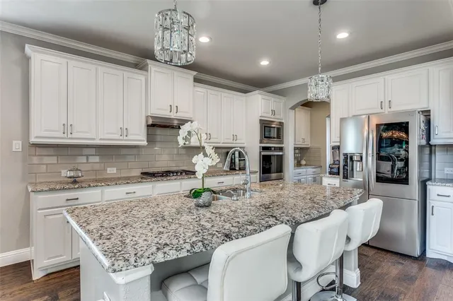 a kitchen with granite countertop a counter space dining table stainless steel appliances and cabinets