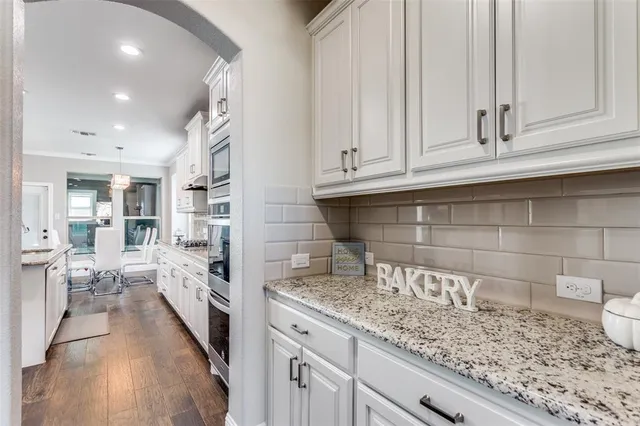a kitchen with granite countertop white cabinets and stainless steel appliances