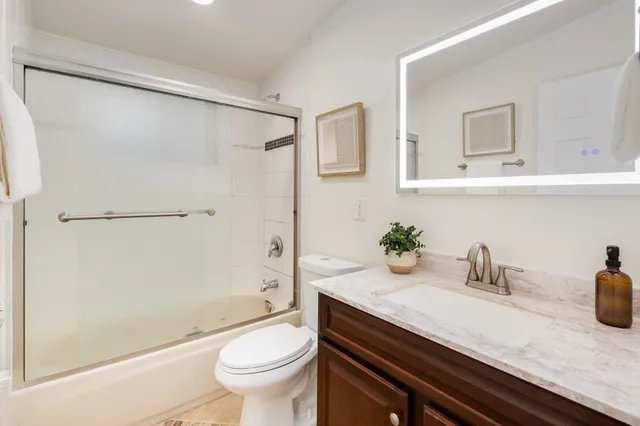 a bath room with a granite countertop sink a toilet and shower