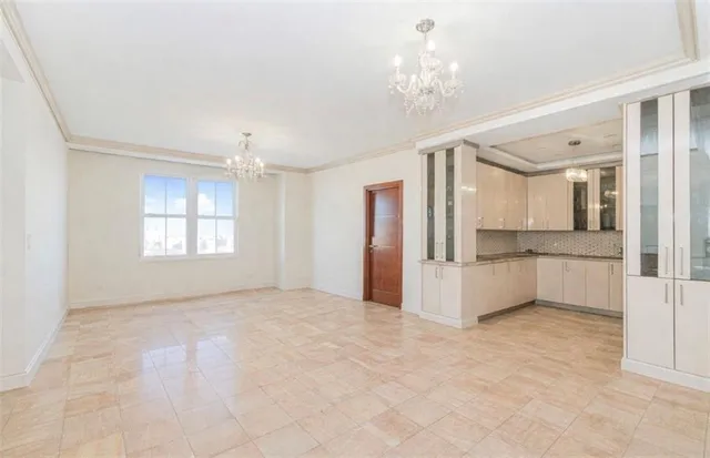 a view of an empty room with window and chandelier