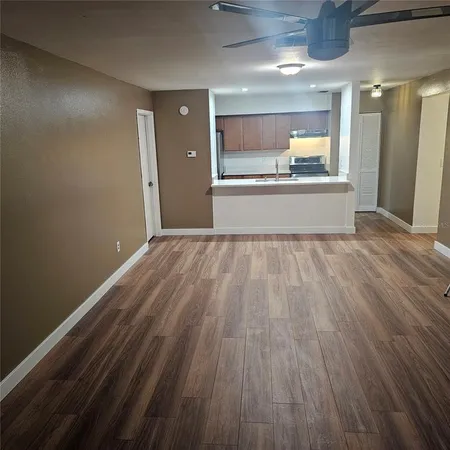 a view of a hallway with a wooden floor and a kitchen