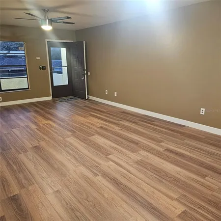 a view of an empty room with wooden floor and a window