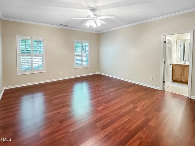 an empty room with wooden floor chandelier fan and windows