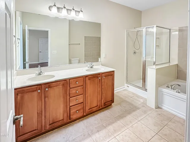 a spacious bathroom with a double vanity sink a large mirror and a bathtub