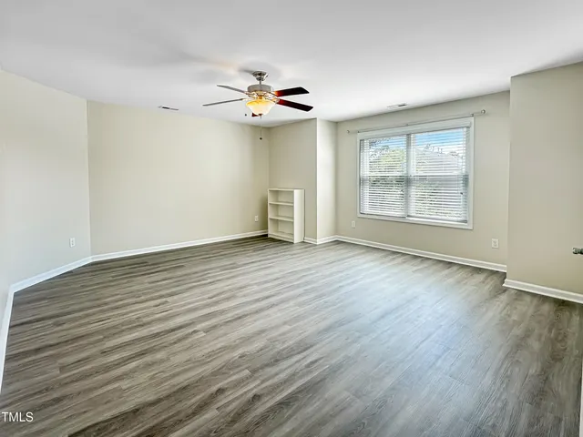 a view of an empty room with a window and wooden floor