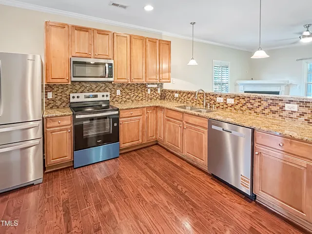 a kitchen with stainless steel appliances granite countertop a stove a sink and a refrigerator