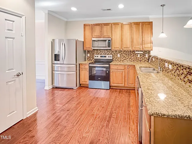 a kitchen with granite countertop wooden floors a stove and a refrigerator