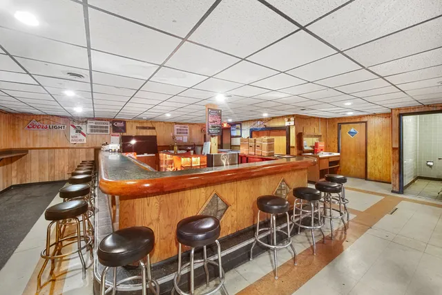 a dining hall with stainless steel appliances kitchen island granite countertop a table chairs in it and wooden floors