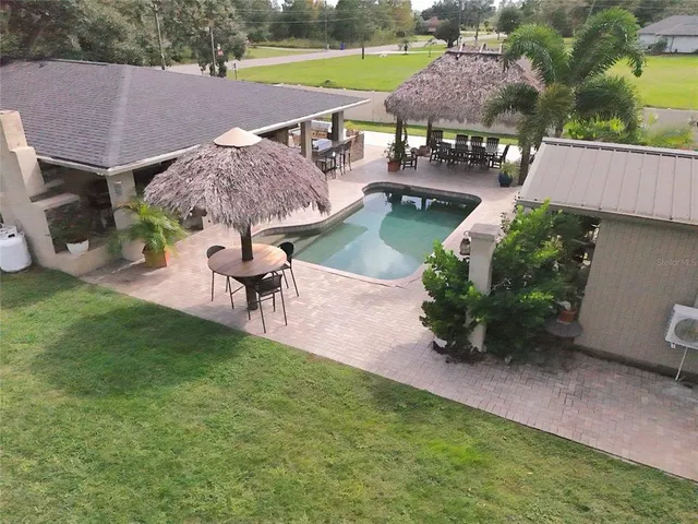 a view of a house with a yard and table and chairs under an umbrella