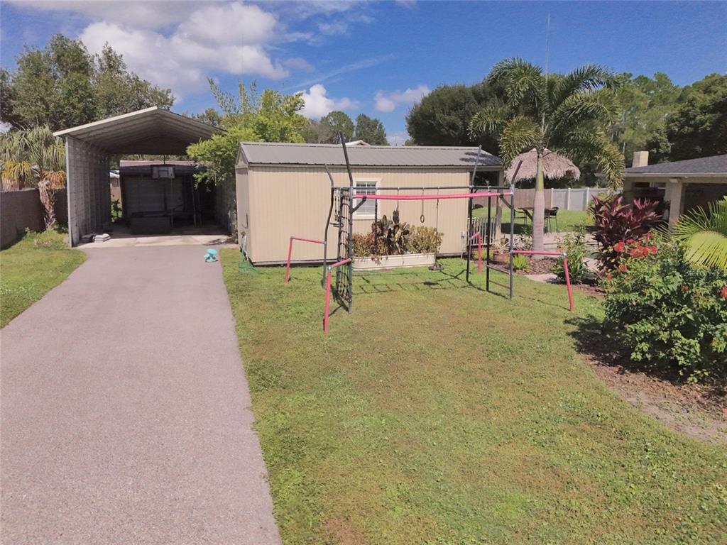 5031 Lakewood Road Sebring, FL 33875 - Photo 6 of 77 a view of a house with a yard and table and chairs under an umbrella