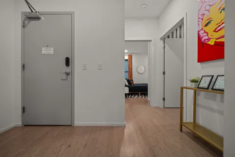 a view of a hallway with wooden floor and a bathroom