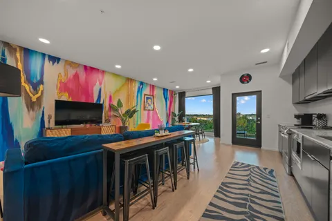 a living room with stainless steel appliances furniture and a flat screen tv