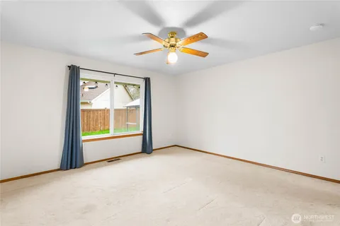 an empty room with a window and a ceiling fan