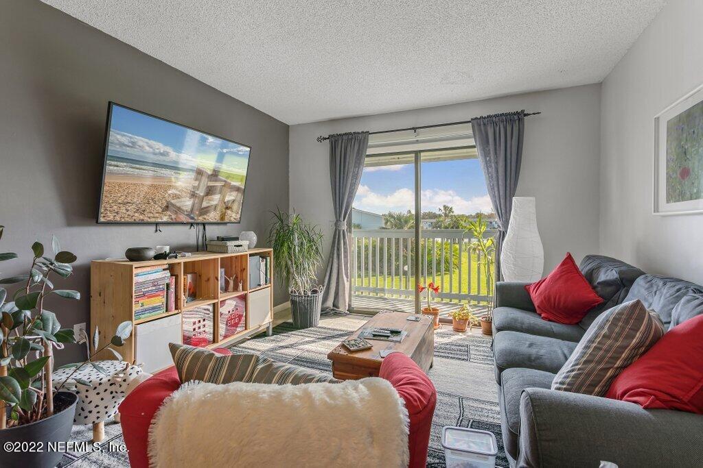 700 West Pope Road, Unit A6 St. Augustine, FL 32080 - Photo 5 of 25 a living room with furniture a flat screen tv and a floor to ceiling window