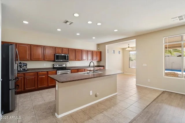 a kitchen with stainless steel appliances granite countertop a sink counter space cabinets and a refrigerator