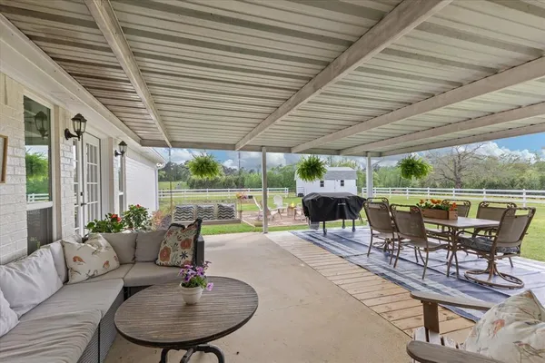 a roof deck with table and chairs couches with wooden floor and fence