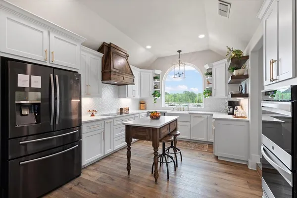 a kitchen with stainless steel appliances granite countertop a refrigerator a stove a sink dishwasher and a refrigerator with wooden floor