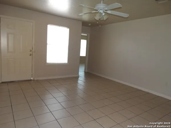 an empty room with windows and fan