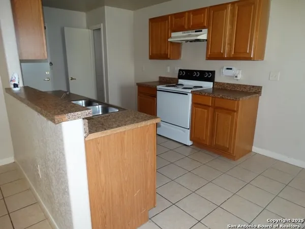 a kitchen with granite countertop a sink a stove and cabinets