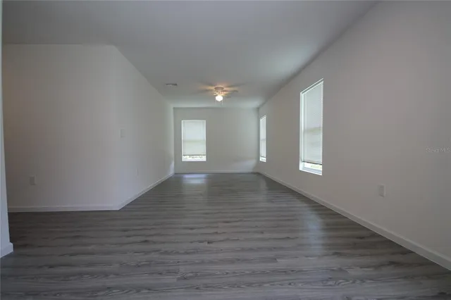 a view of an empty room with wooden floor and window