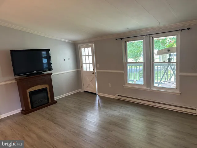 an empty room with windows tv and wooden floor