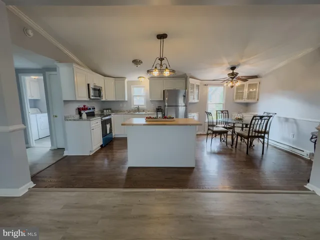 a view of a dining room and livingroom with furniture wooden floor a rug and a chandelier