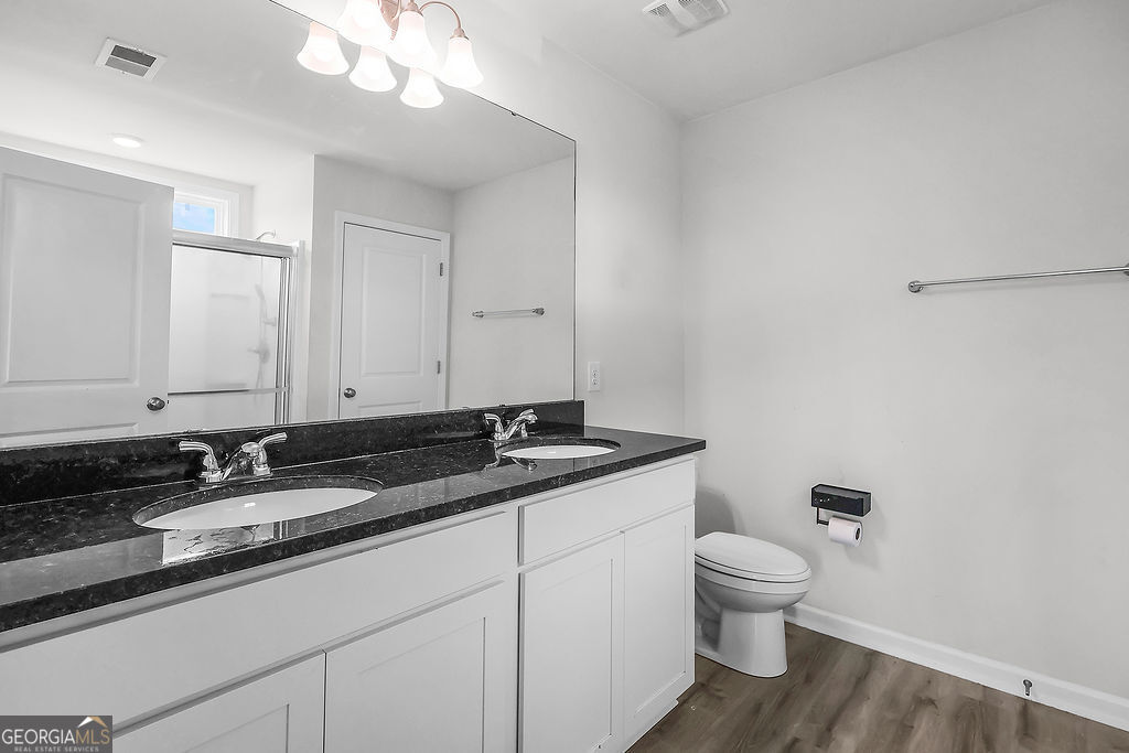 231 Caroline Way Guyton, GA 31312 - Photo 23 of 47 a bathroom with a granite countertop sink a toilet and a mirror