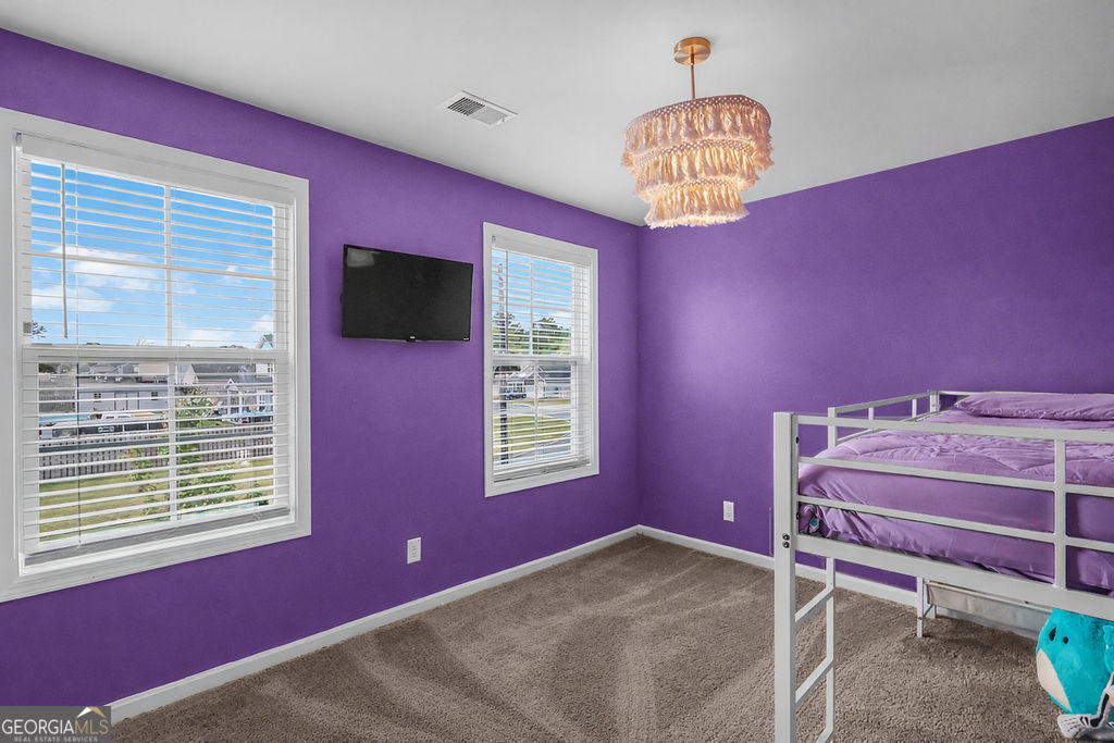 231 Caroline Way Guyton, GA 31312 - Photo 26 of 47 a room with a bed and a chandelier