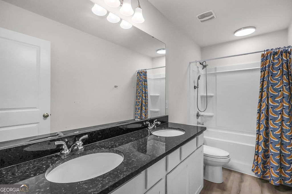 231 Caroline Way Guyton, GA 31312 - Photo 29 of 47 a bathroom with a double vanity sink toilet a mirror and shower