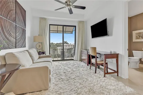 a living room with furniture a flat screen tv and a floor to ceiling window