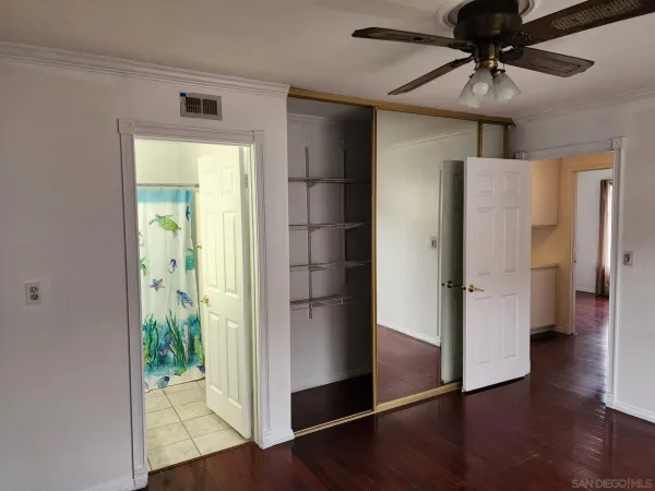 a view of a hallway with wooden floor and a refrigerator in a kitchen